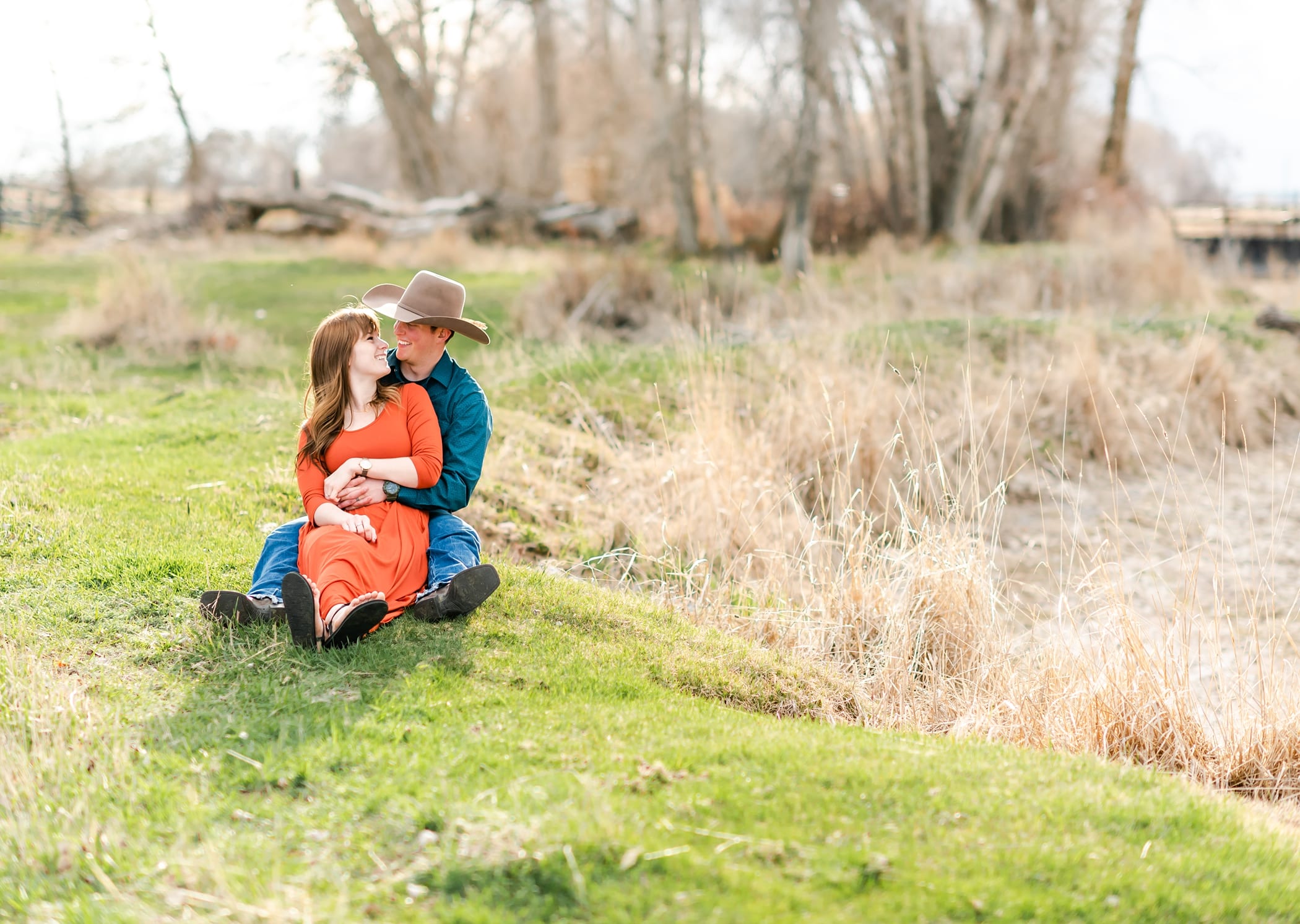 Rustic and country engagement session with cowboy hat and open field