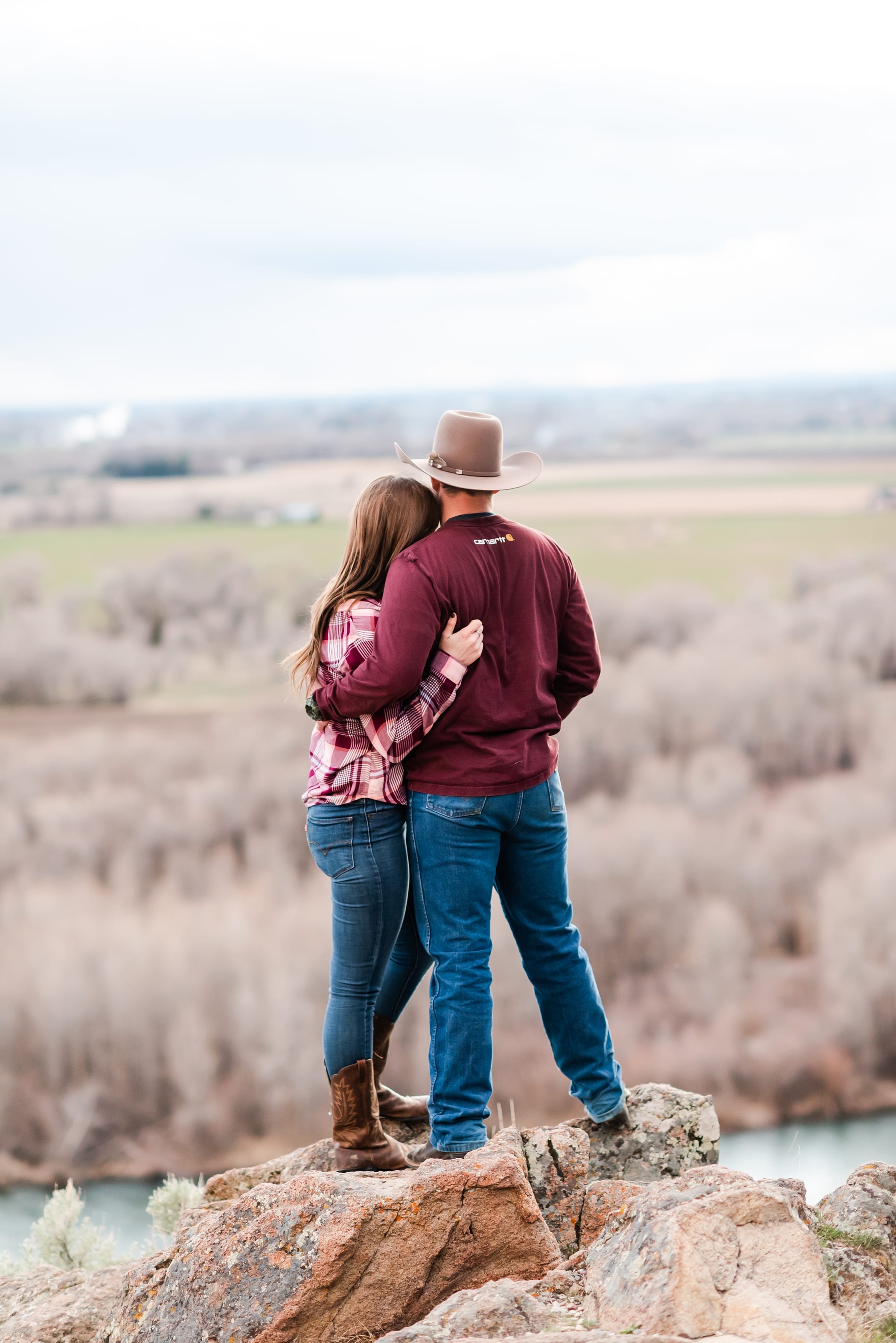Rustic and country engagement session with cowboy hat and open field