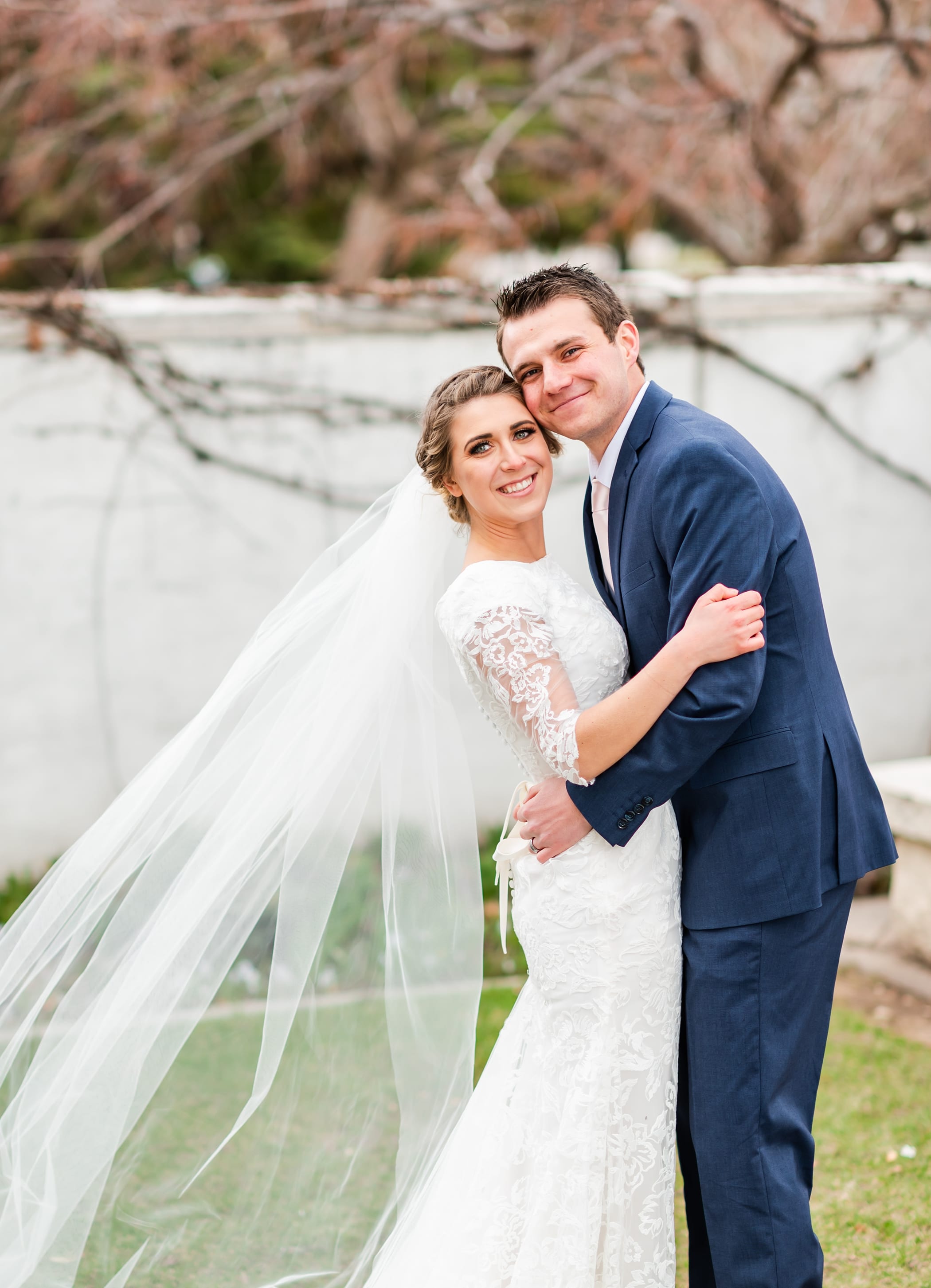 Classic wedding portrait with lace three quarter length sleeves and long veil with navy suit